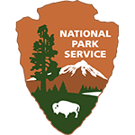 National-Park-Service-Logo The official logo of the National Park Service (NPS): an arrowhead shape with a mountain peak inside, flanked by pine trees, all in green. The words 'National Park Service' are inscribed in white along the top edge of the arrowhead.